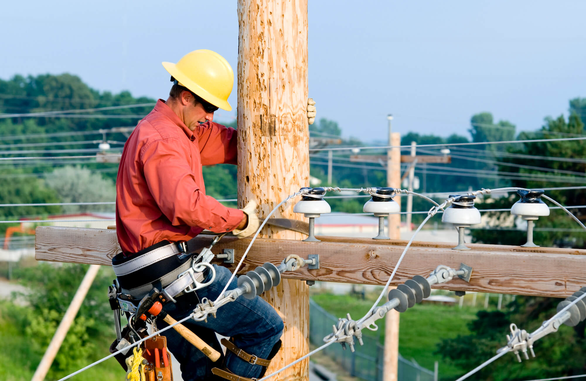 Lineman climbing wooden utility pole to carry out maintenance Lineman climbing wooden utility pole to carry out maintenance